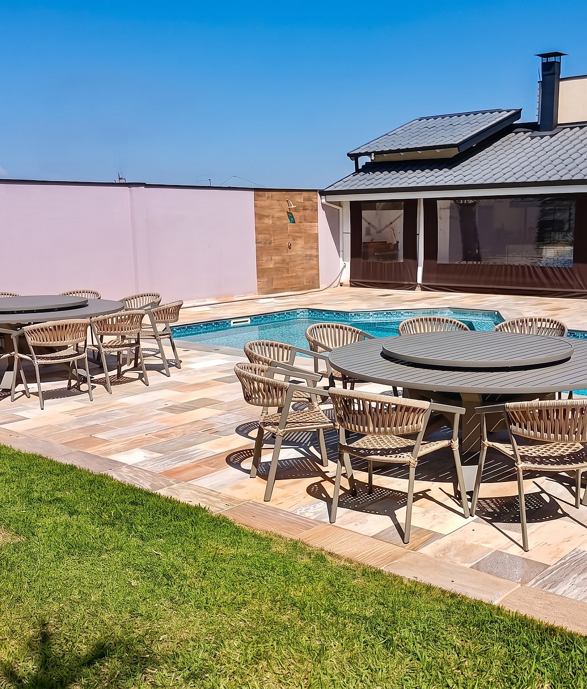 Área de piscina residencial com mesas e cadeiras da Poços em volta da borda